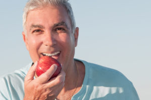 affordable dentures and implants example of man with apple