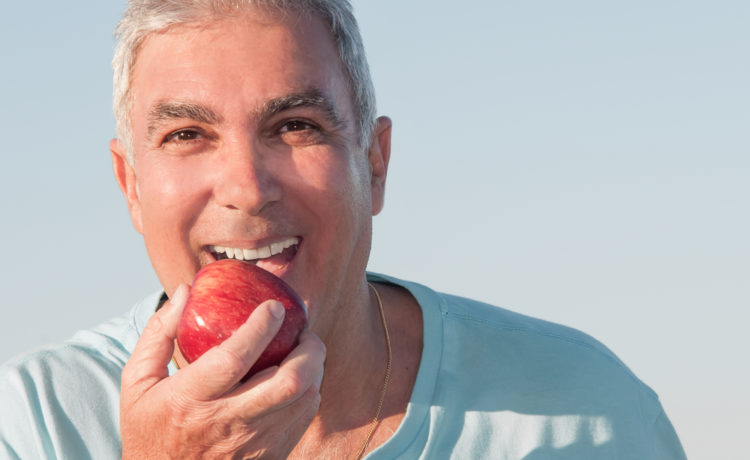affordable dentures and implants example of man with apple