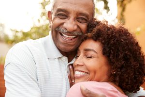 affordable dentures & implants man and woman hugging and smiling