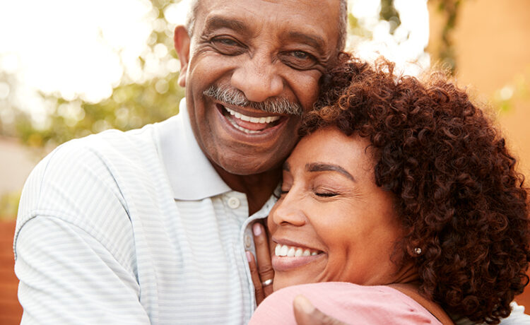 affordable dentures & implants man and woman hugging and smiling