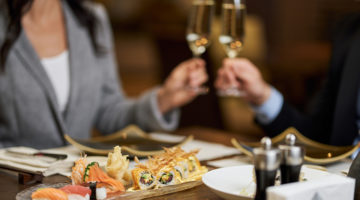 a couple shares a platter of sushi and glass of wine; date night activity
