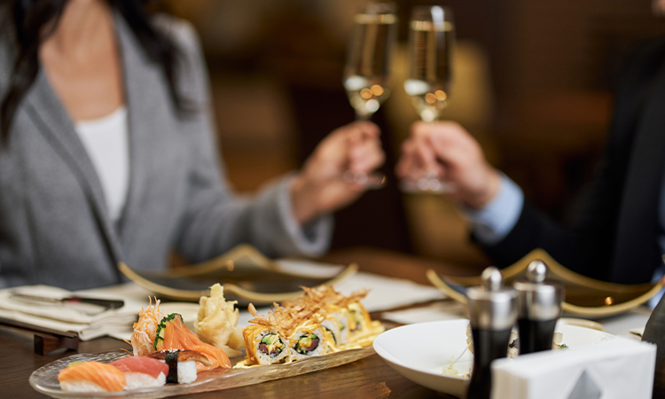 a couple shares a platter of sushi and glass of wine; date night activity