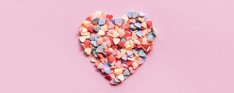 candied hearts in a heart shape with pink background. A perfect treat to have for Galentines Day activities/