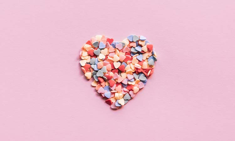 candied hearts in a heart shape with pink background. A perfect treat to have for Galentines Day activities/