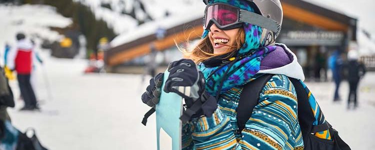 a girl happily geared up with all the essential snowboarding gear from the snowboarding gear list