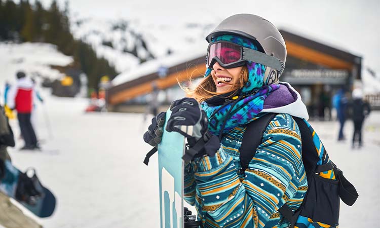 a girl happily geared up with all the essential snowboarding gear from the snowboarding gear list