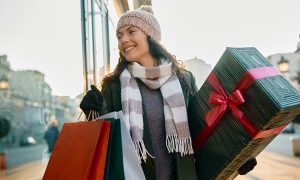 woman in winter clothes carrying christmas presents through mall for a blog about the best christmas shopping in bend